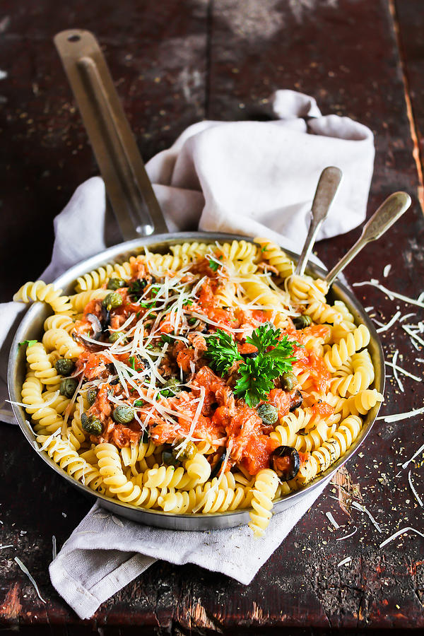 Fusilli pasta dish with tuna fish, tomato sauce, capers, black olives and parmesan cheese in a cooking pan on a wooden table, selective focus #2 Photograph by Anna Kurzaeva