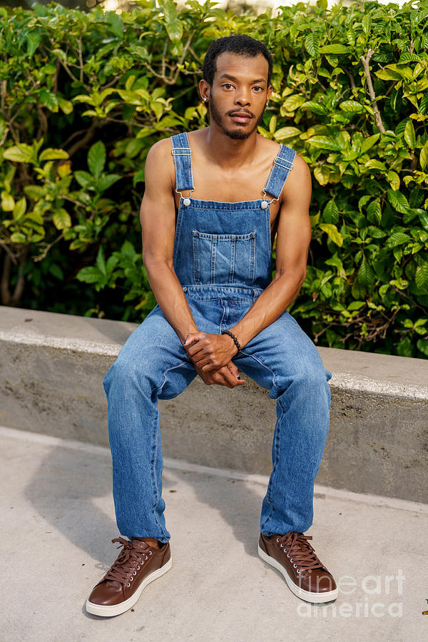 Handsome African American man posing in overalls at a park scene ...