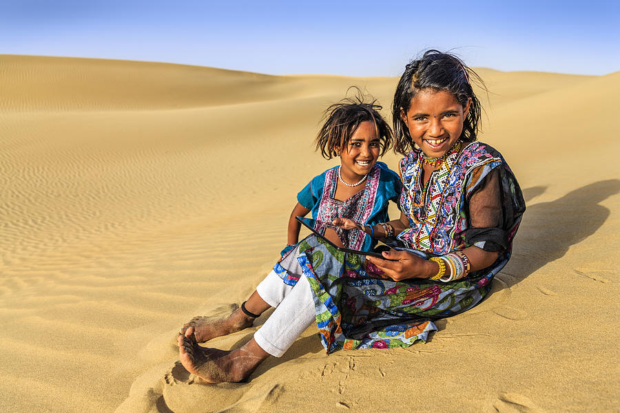 Happy Indian little girls using digital tablet, desert village, India #2 Photograph by Hadynyah