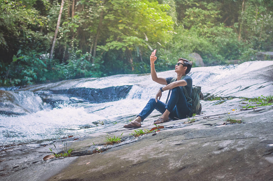 Hiker with backpack and laptop and phone at  waterfall  the forest. #2 Photograph by Primeimages
