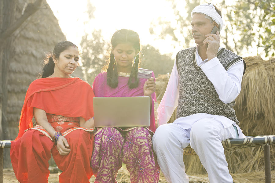 Indian family with laptop and credit card on village bed #2 Photograph by Triloks