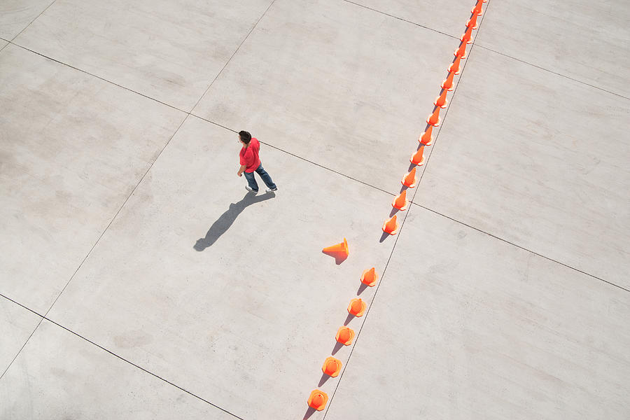 Man walking away from row of traffic cones with one misplaced #2 Photograph by Martin Barraud