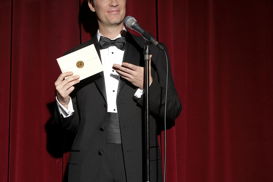 Man wearing tuxedo standing on stage, showing envelope, mid section #2 Photograph by Leonard Mc Lane