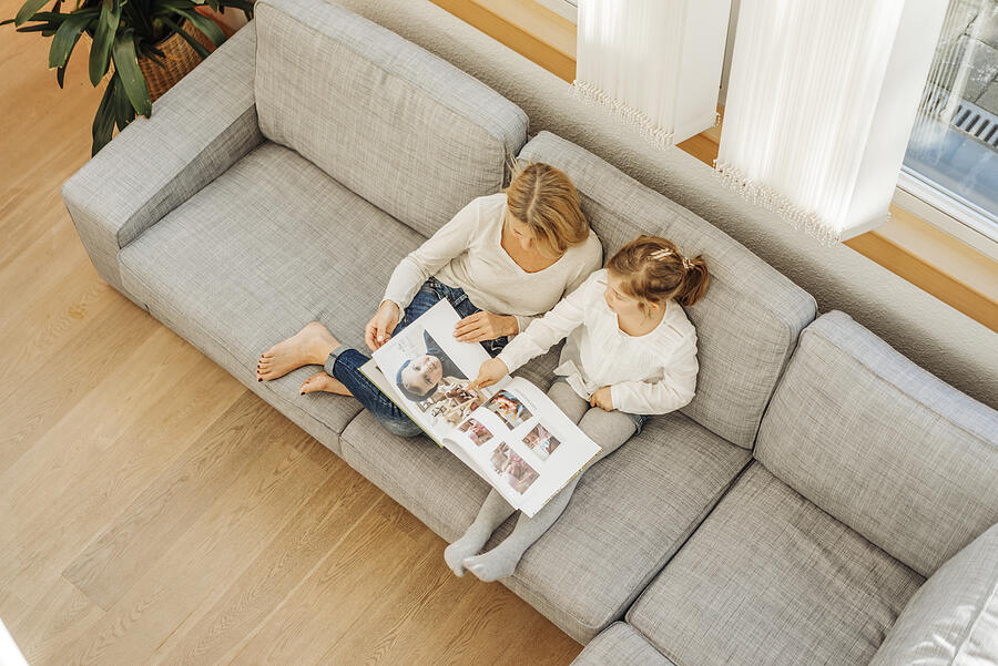 Mature woman and girl at home looking at photo album on couch #2 Photograph by Westend61