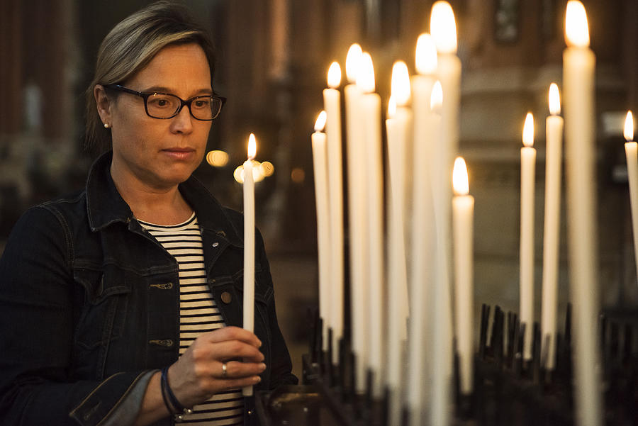 Mature woman lighting candles in church. #2 Photograph by Martinedoucet