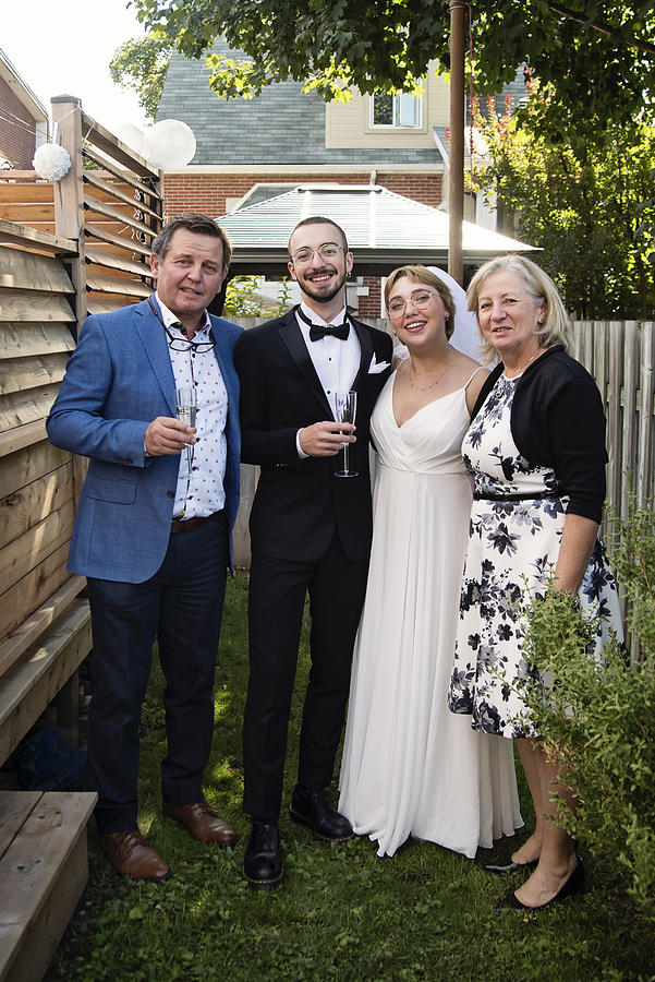 Millennial newlywed couple posing with grandparents in backyard. #2 Photograph by Martinedoucet