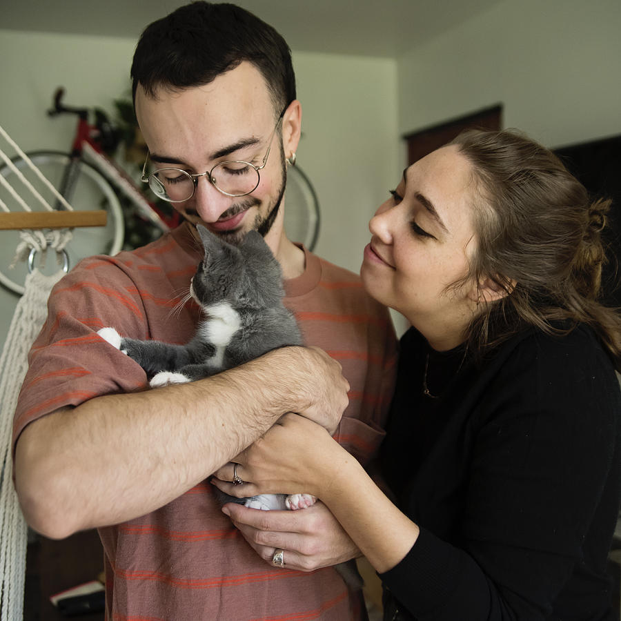 Portrait of millennial couple and newly adopted kitten at home. #2 Photograph by Martinedoucet