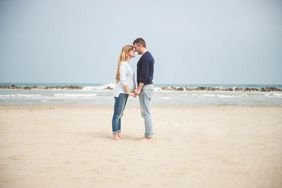 Pregnant couple on the beach. Hand in hand. Casual clothes. #2 Photograph by © Samantha Carrirolo