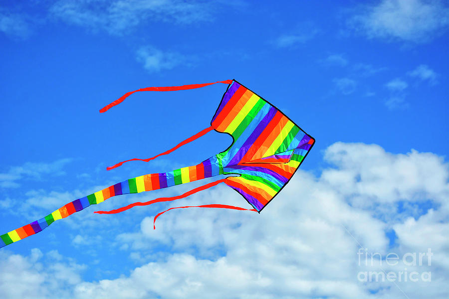 Rainbow coloured kite against blue skies. #2 Photograph by Milleflore Images