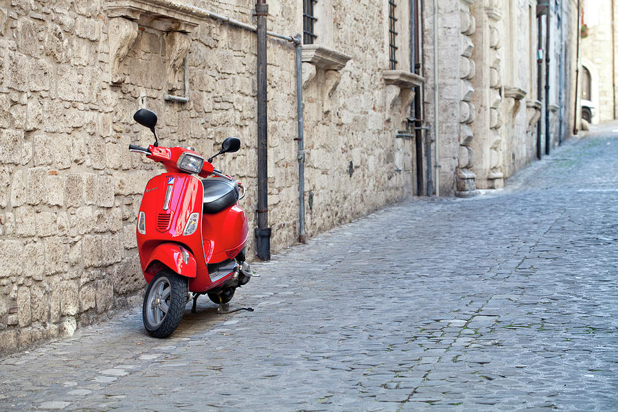 Red Vespa Scooter Parked Next to Brick Wall