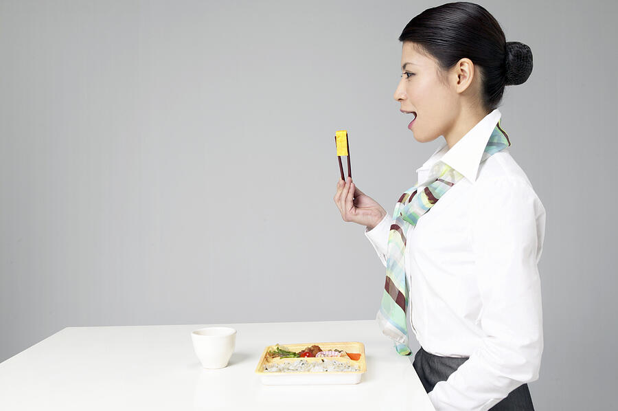 Side View of a Woman Sitting at a Table Eating Food With Chopsticks #2 Photograph by Mash