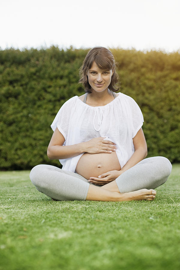 Smiling pregnant woman sitting on grass #2 Photograph by Tomas Rodriguez