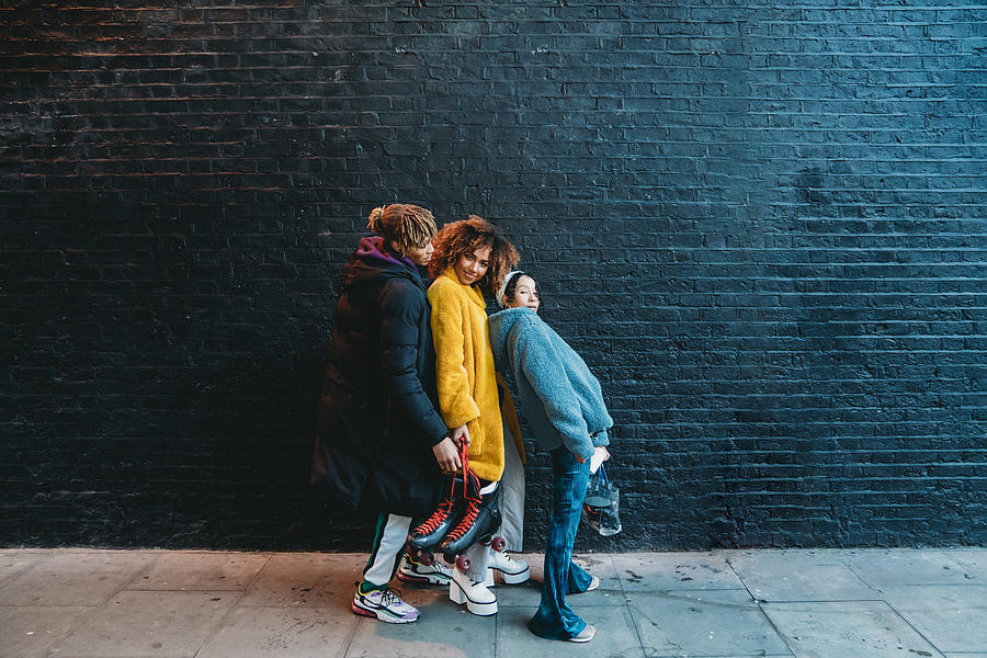 Three friends dancing in the city against a black brick wall #2 Photograph by FilippoBacci