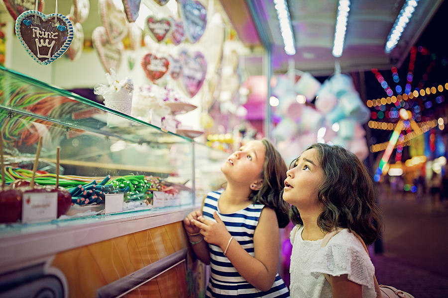 Two little girls are looking sweets in the candy wagon at the fun fair #2 Photograph by Praetorianphoto