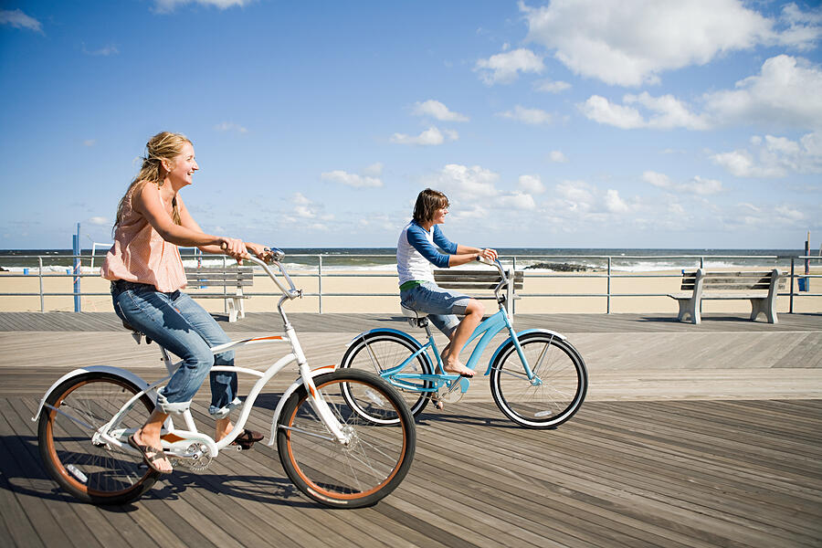 Two women cycling on boardwalk #2 Photograph by Image Source