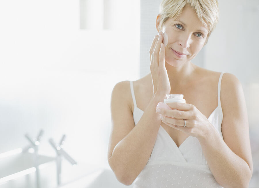 Woman applying face cream in the morning #2 Photograph by Paul Bradbury