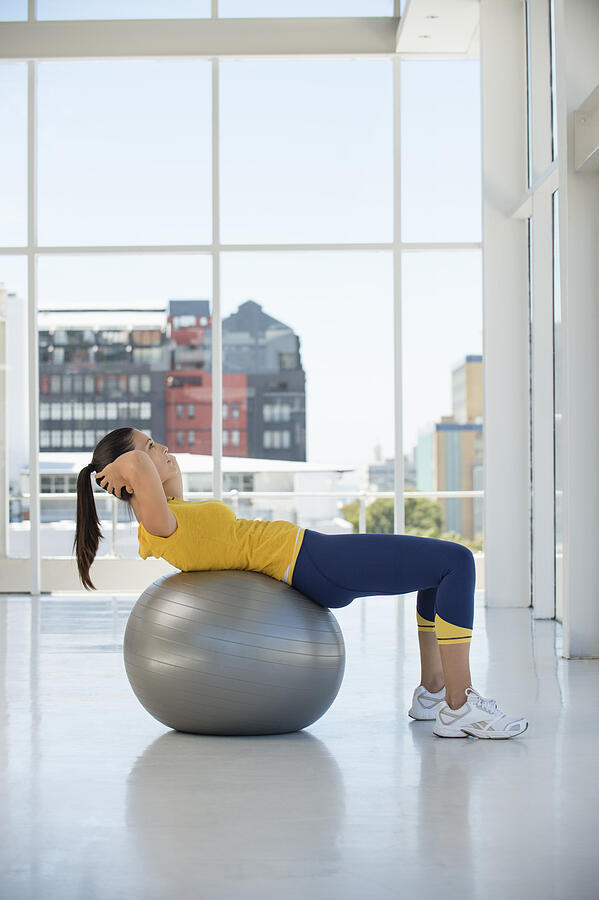 Woman exercising on a fitness ball in a gym #2 Photograph by Eric Audras