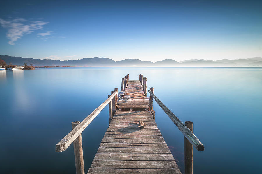 Wooden pier or jetty and lake at sunrise. Torre del lago Puccini ...