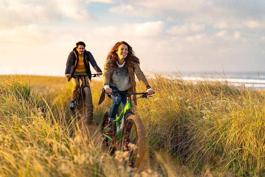 Young couple ride fat bikes on coastal trail #2 Photograph by AscentXmedia