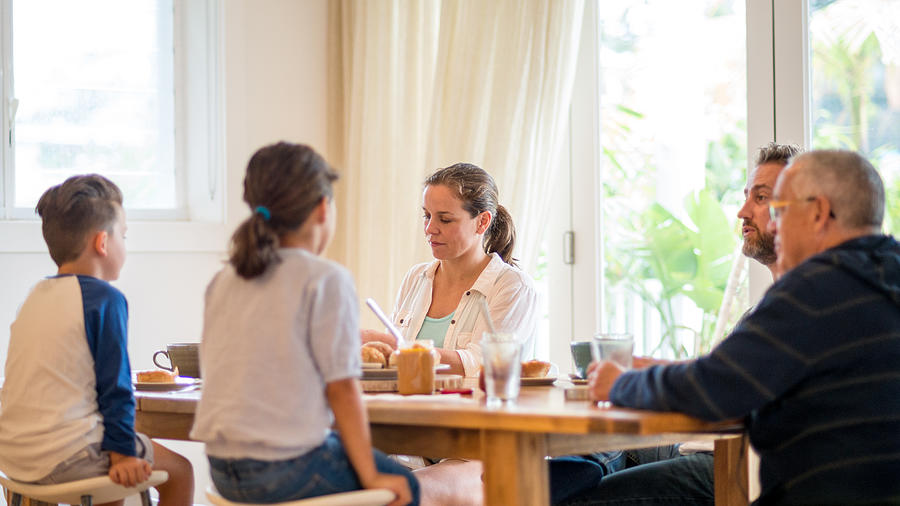 Young family having pleasant conversation during breakfast in the dining room #2 Photograph by Lovro77