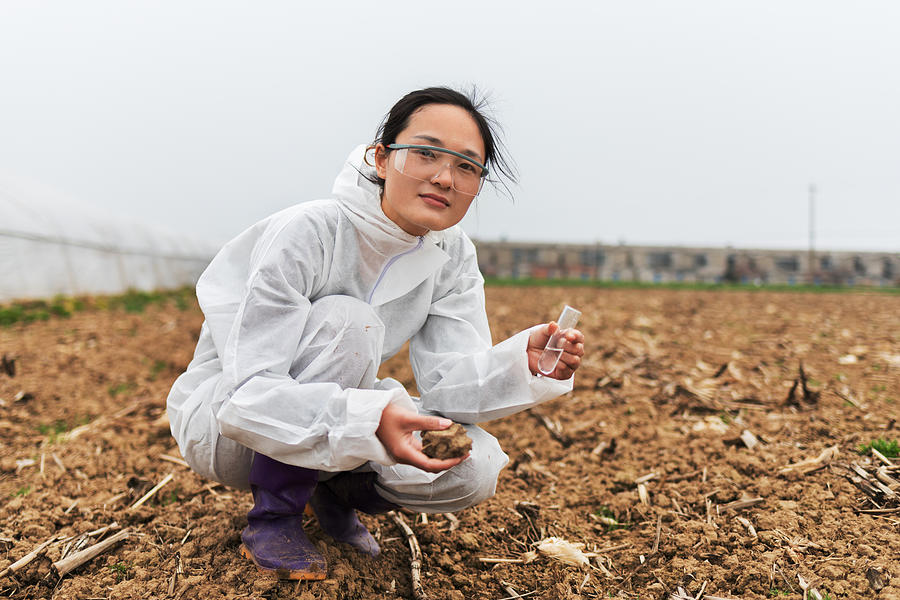 Young female scientist holding test tube and soil Photograph by Qi Yang