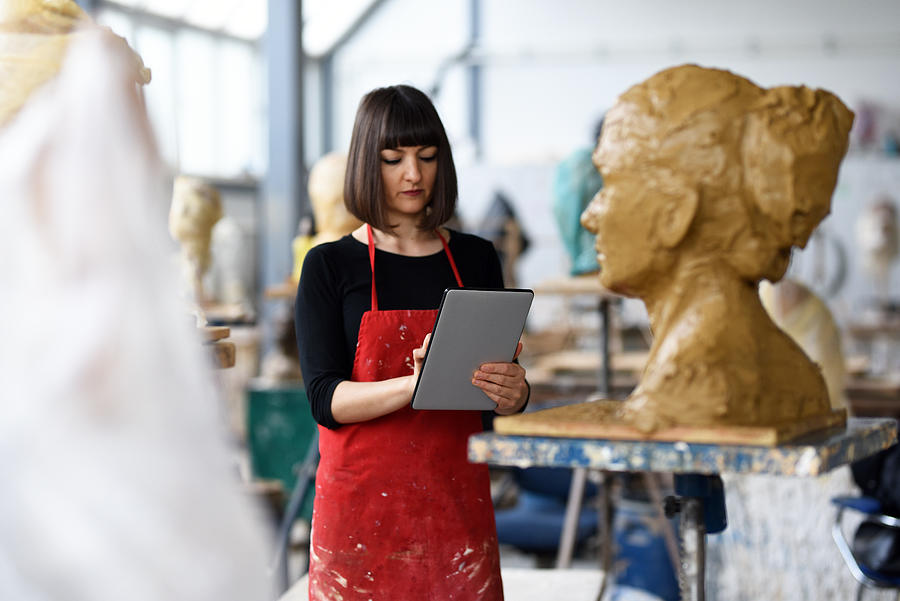 Young Female Sculptor is working with digital tablet in her studio #2 Photograph by Baranozdemir