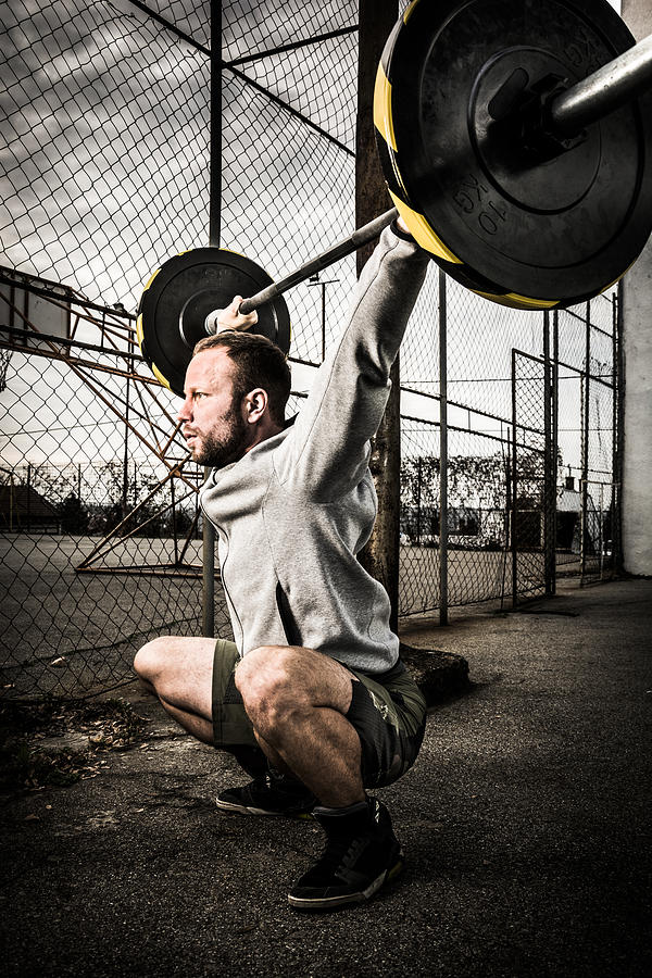Young man on cross training lifting weights #2 Photograph by Zoran Kolundzija