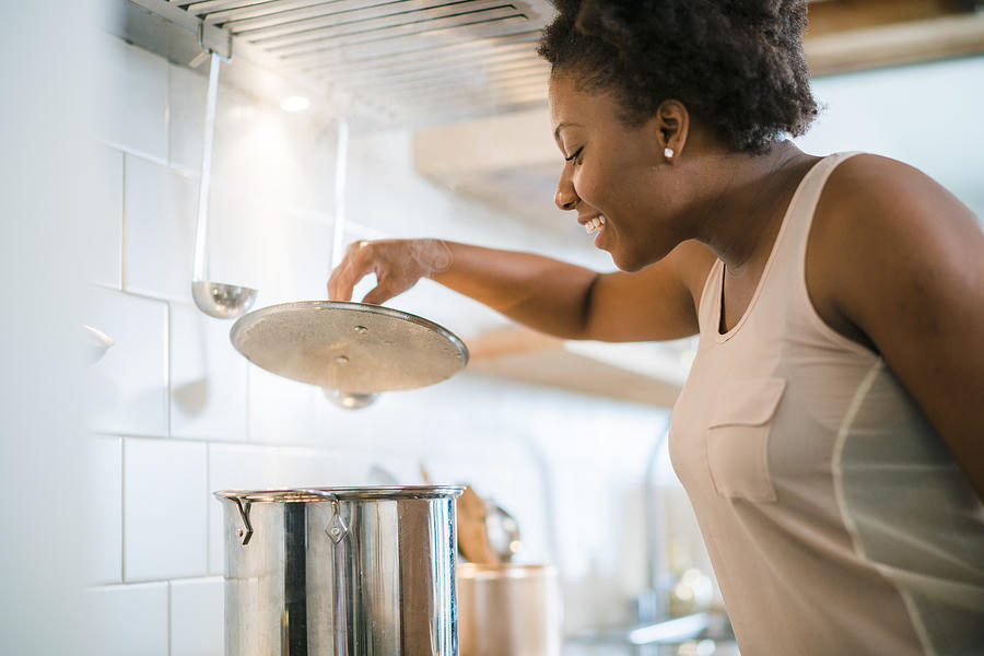 Young pretty black woman make soup in kitchen #2 Photograph by Alex Potemkin