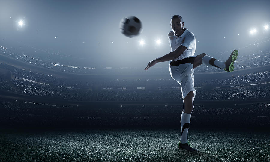 Soccer player kicking ball in stadium #23 Photograph by Dmytro Aksonov