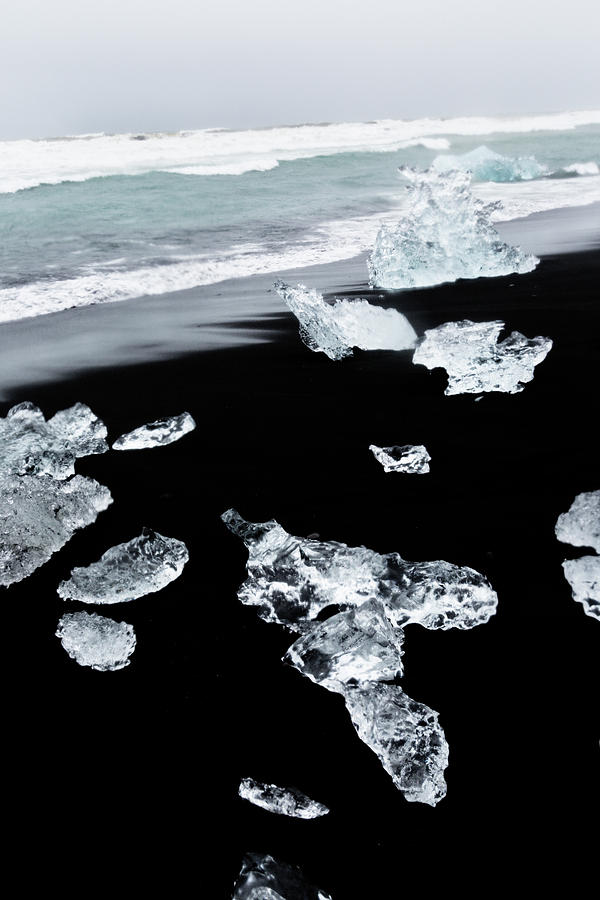 Glistening chunks of ice wash up on a lava black sand beach in t #6  Photograph by Bruce Beck - Pixels