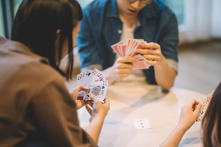 Asian Chinese Friends Playing Poker Cards Game In Living Room #3 Photograph by Edwin Tan