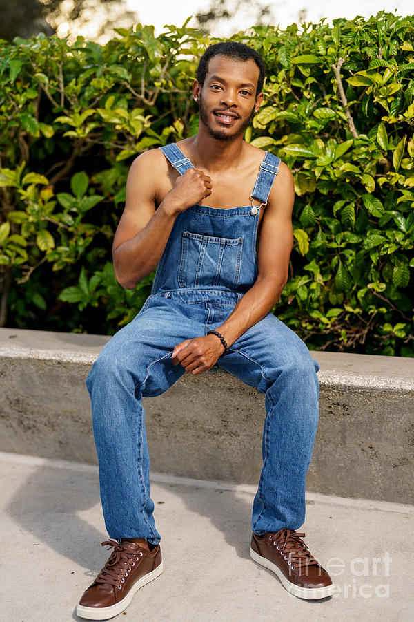 Handsome African American man posing in overalls at a park scene ...