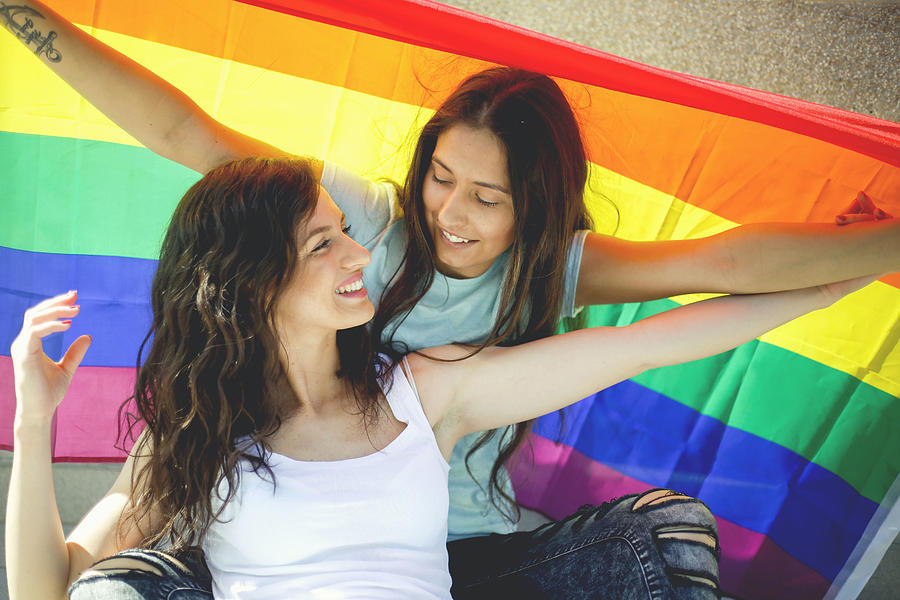 LGBT Lesbian couple moments happiness concept. Holding rainbow flag outdoors #3 Photograph by MarijaRadovic