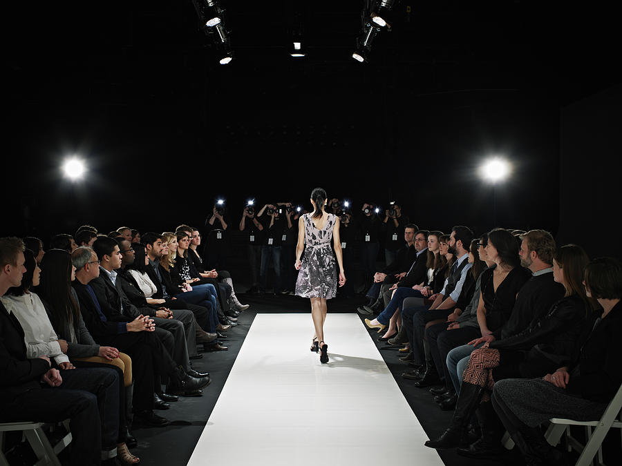 Model walking down catwalk during fashion show #3 Photograph by Thomas Barwick