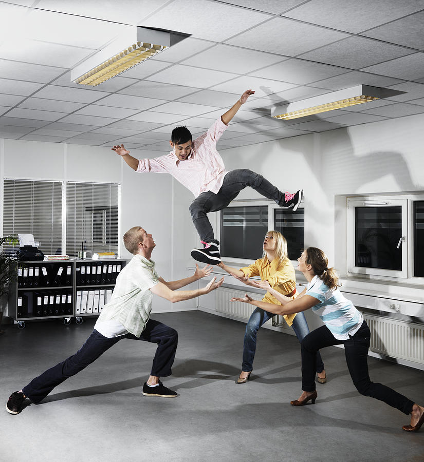 3 People in an office throwing a 4th person in the Photograph by Henrik Sorensen