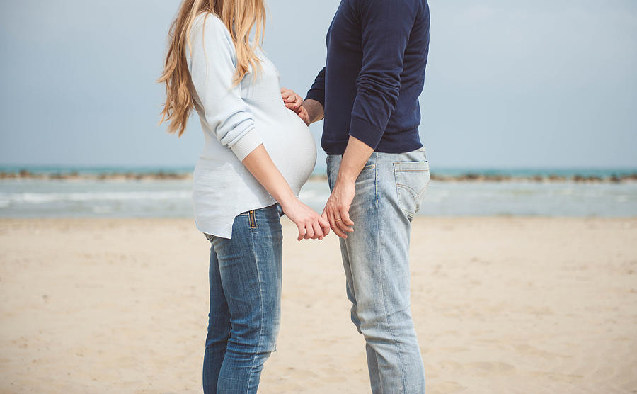Pregnant couple on the beach. Hands on the belly. Casual clothes. Hand in hand. #3 Photograph by © Samantha Carrirolo