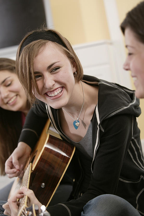 Teenage girl playing guitar with friends #3 Photograph by Comstock Images