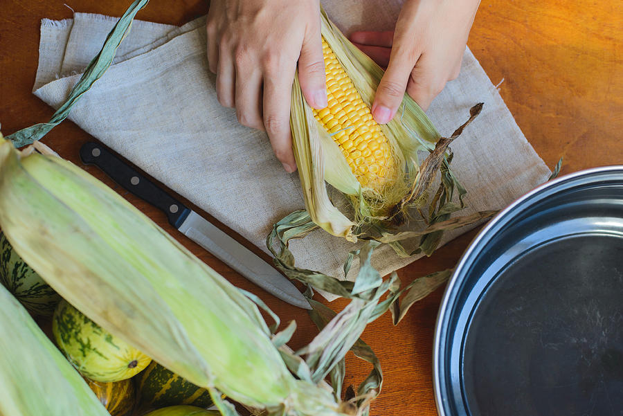 Top View Of Woman Prepares Corn For Cooking In Bowl #3 Photograph by Apagafonova