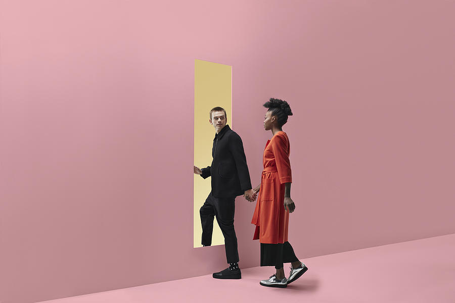 Woman & man holding hands, approaching rectangular opening in coloured wall #3 Photograph by Klaus Vedfelt