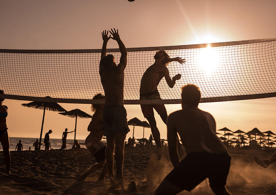 Young friends having fun while playing beach volleyball at sunset. #3 Photograph by Skynesher