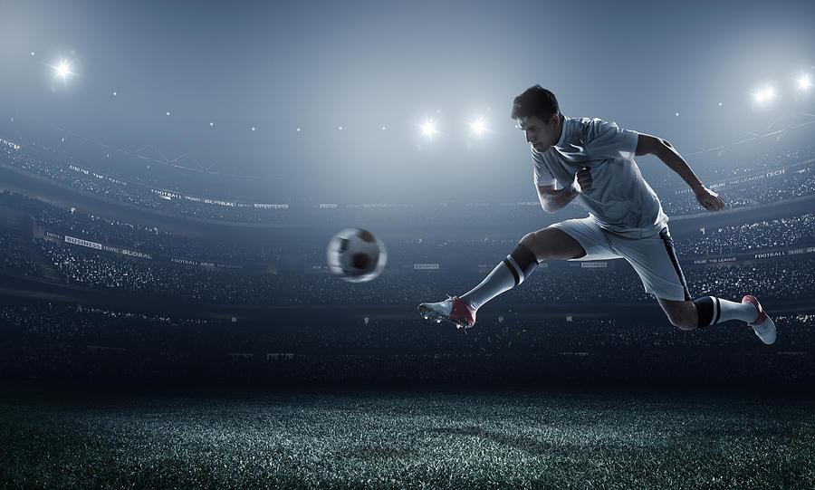 Soccer player kicking ball in stadium #31 Photograph by Dmytro Aksonov