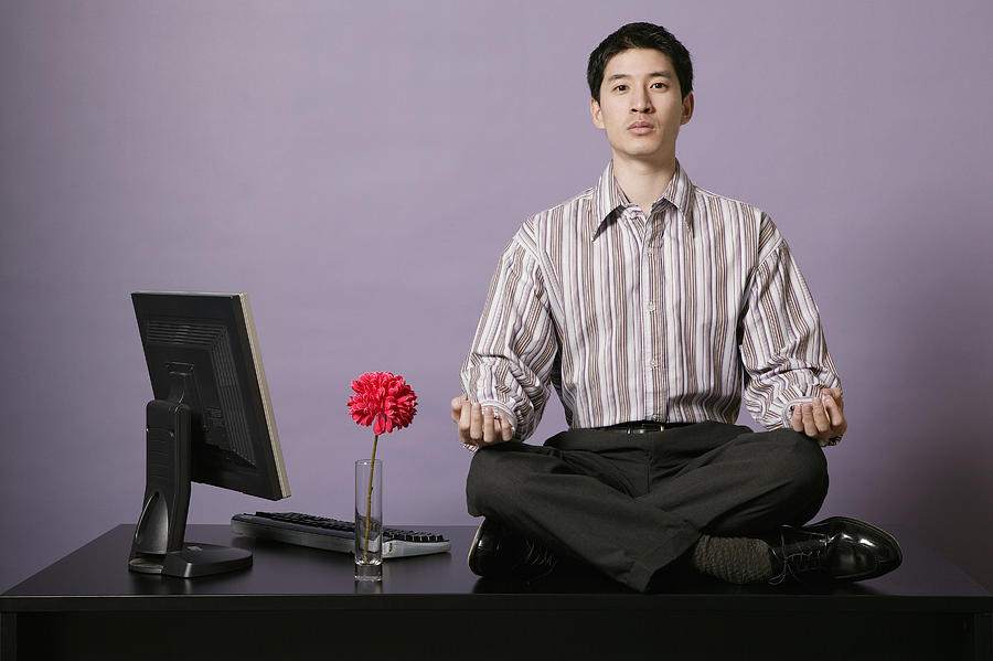 Businessman meditating on top of desk #4 Photograph by Comstock Images