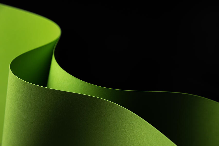 Green, wave paper craft on a black background - closeup. Photograph by ...