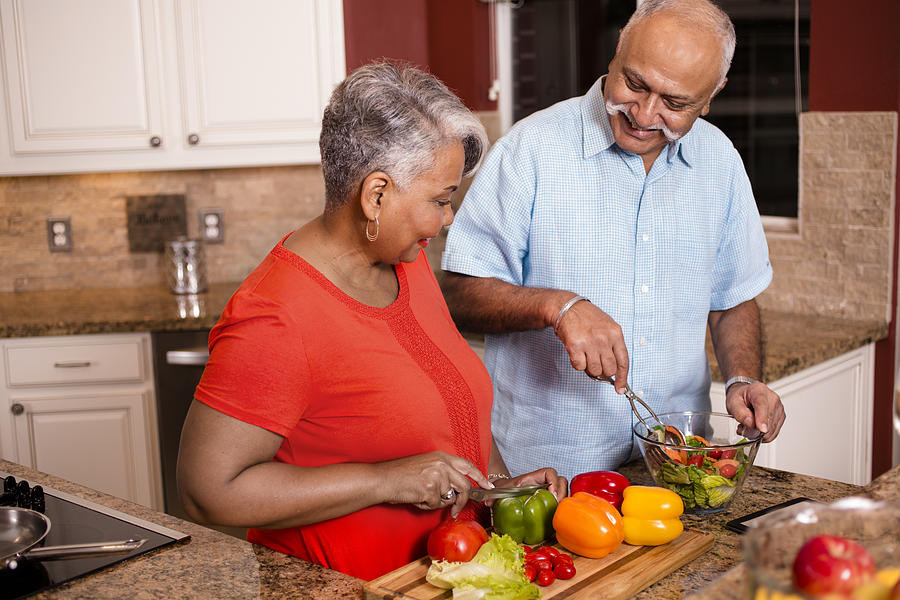 Happy senior adult couple cooking together in home kitchen. #4 Photograph by Fstop123