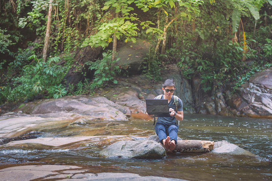 Hiker with backpack and laptop and phone at  waterfall  the forest. #4 Photograph by Primeimages