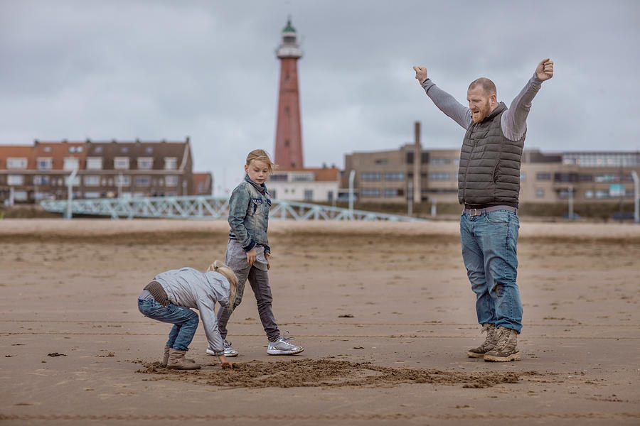 Single father and his daughters playing family games on a winter beach #4 Photograph by Lorado