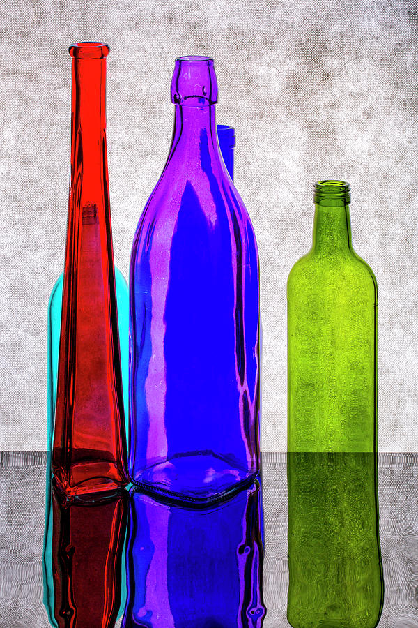 Still life with colored bottles on a reflective surface Photograph by ...