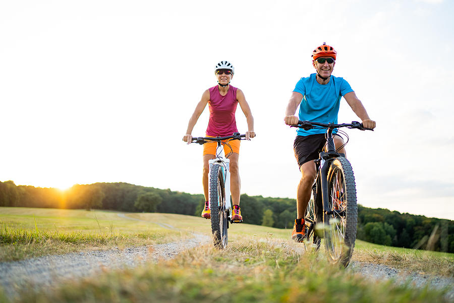 40-50 Years Old Sporty Couple Cycling On Electric Mountain Bikes In Rural Environment Photograph by Amriphoto