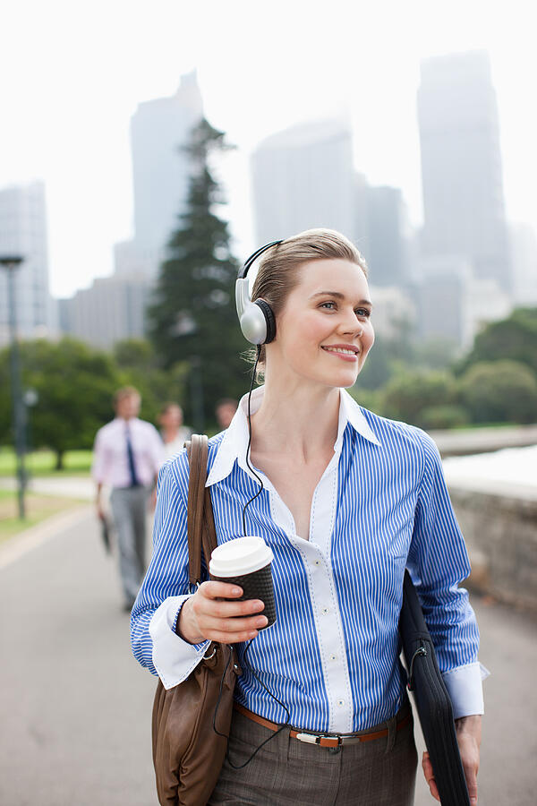 Businesswoman listening to headphones and carrying coffee #5 Photograph by Paul Bradbury