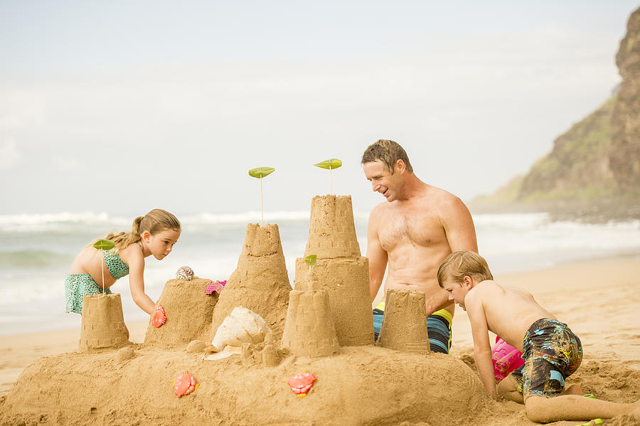 Family building a sandcastle on the beach in Hawaii #5 Photograph by FatCamera